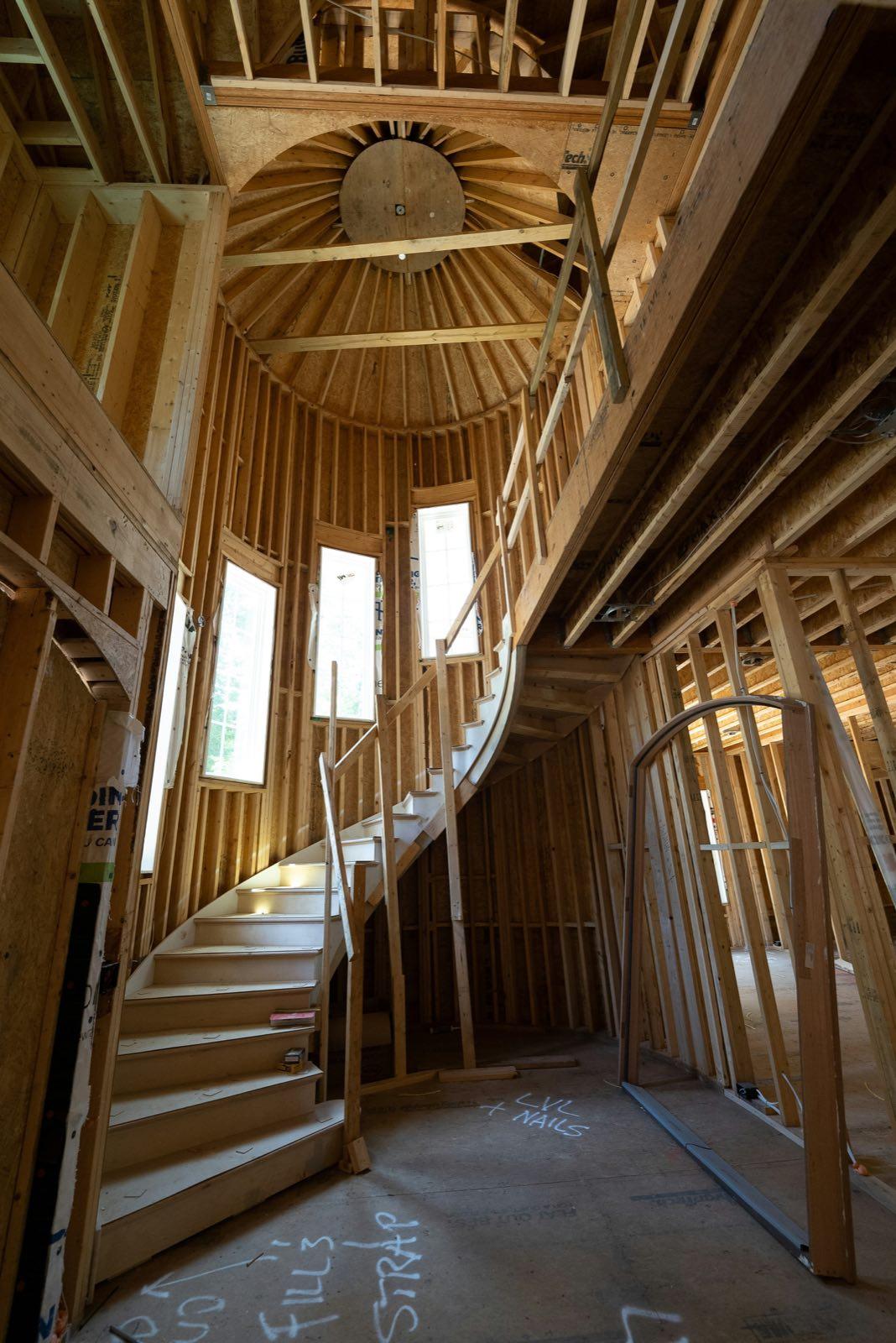 Curved staircase in a round stud-framed stair tower inside a house under construction