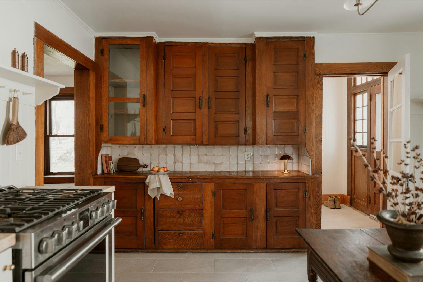 Restored kitchen with original oak cabinetry, tile backsplash, and a professional gas range
