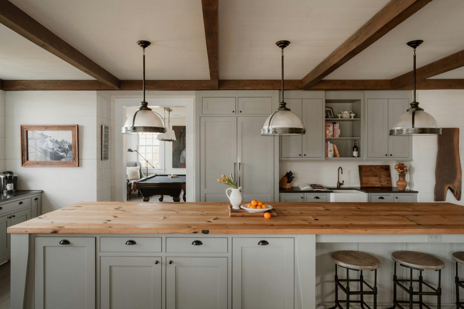 Farmhouse kitchen with exposed ceiling beams, sage cabinetry, and a reclaimed wood island