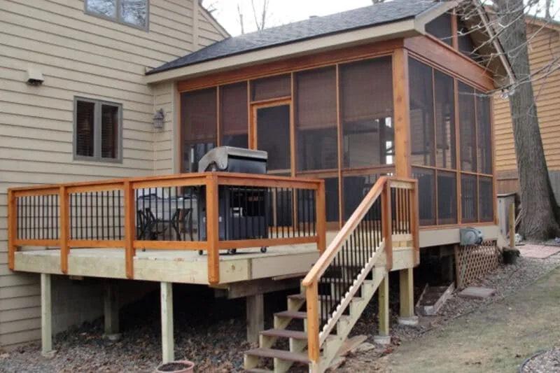 Cedar-framed screened porch and raised deck with stairs on a tan-sided house