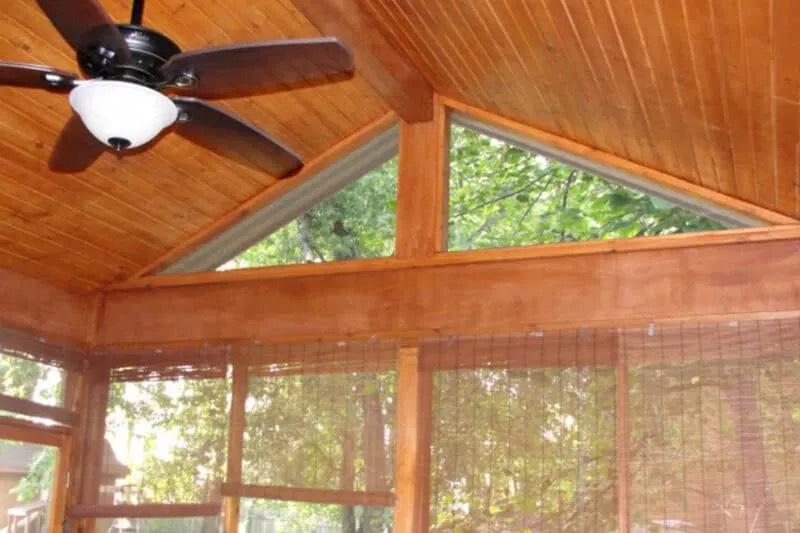 Screened porch interior with vaulted tongue-and-groove wood ceiling, ceiling fan, and triangular gable screens