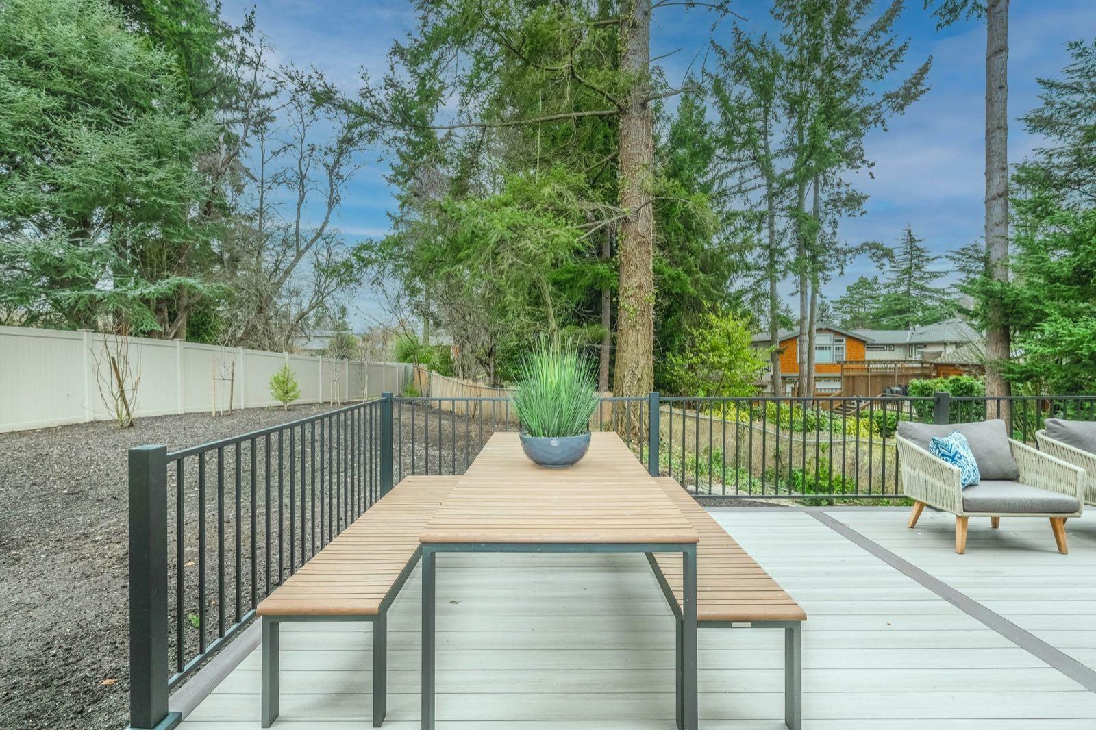 Composite deck with dining table and black metal railing