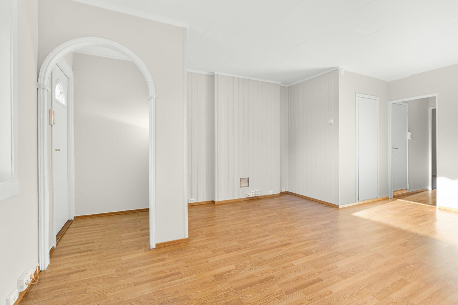 Oak-look floor running past a white arched entry alcove toward two interior doors