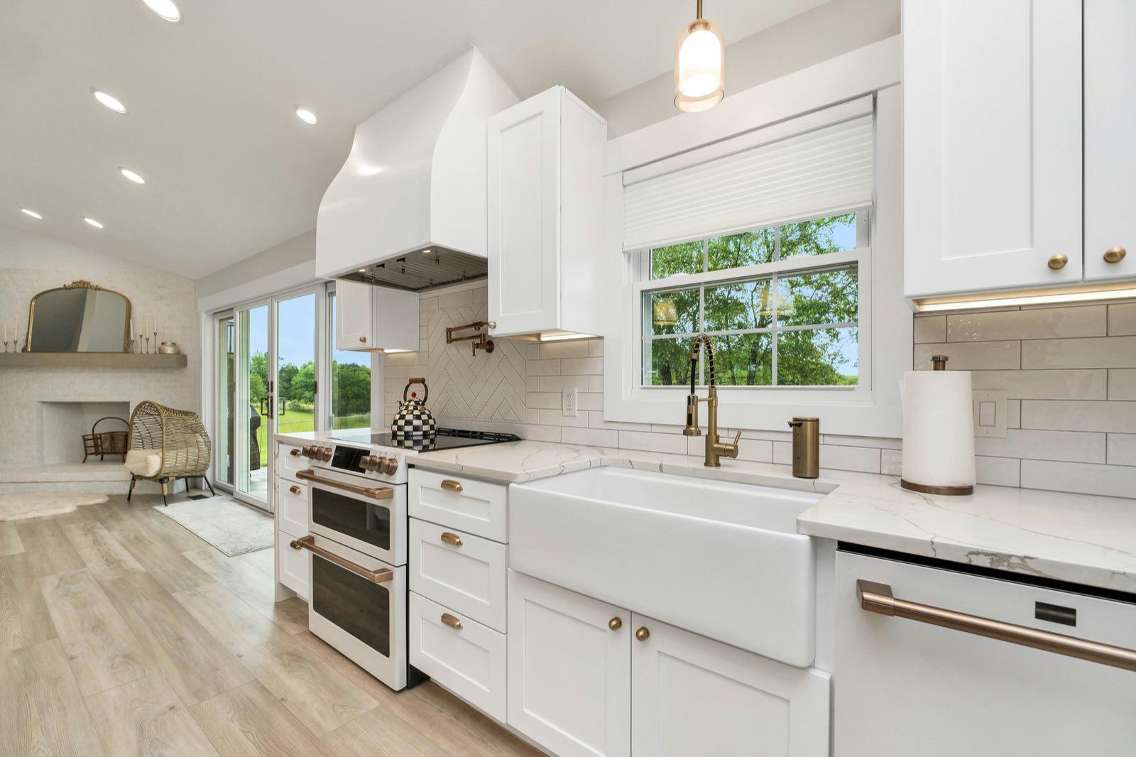 Cooking zone with white shaker cabinets, farmhouse sink, brass faucet, subway tile backsplash, and double wall oven