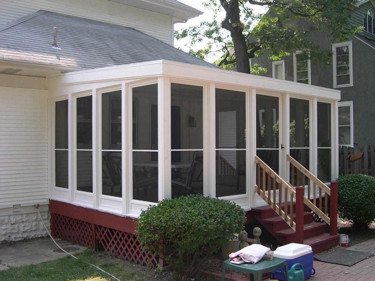 White screened porch with red lattice skirting and wood entry steps on a white-sided house