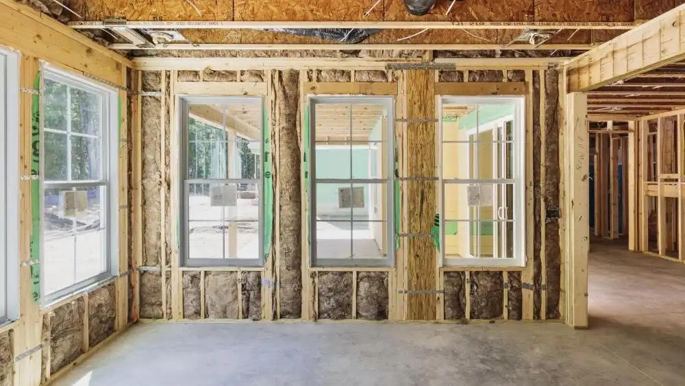 New white double-hung windows set in an open stud wall with insulation batts