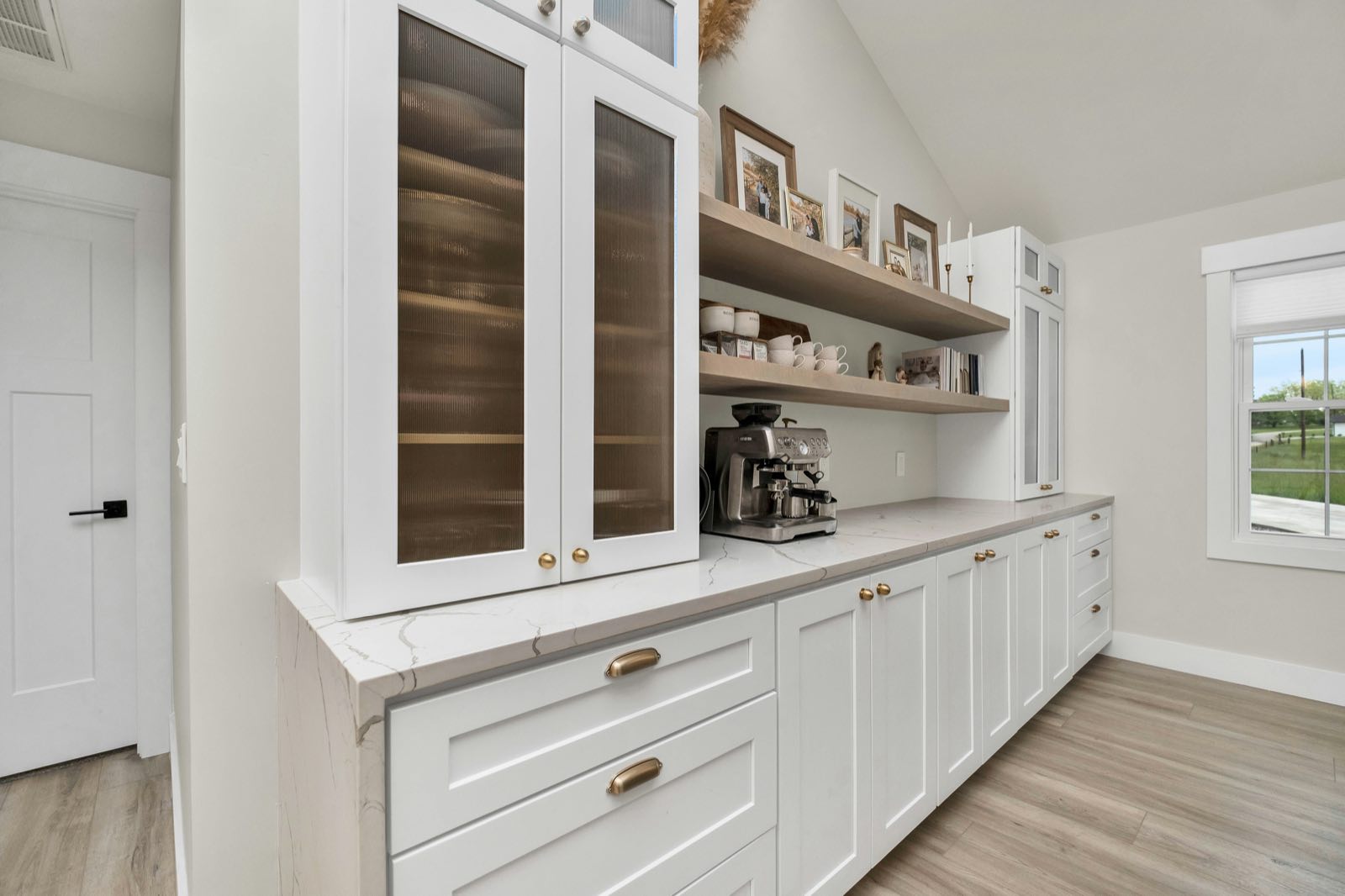 Custom butler's pantry with glass-front upper cabinets, open floating shelves, and white quartz countertop