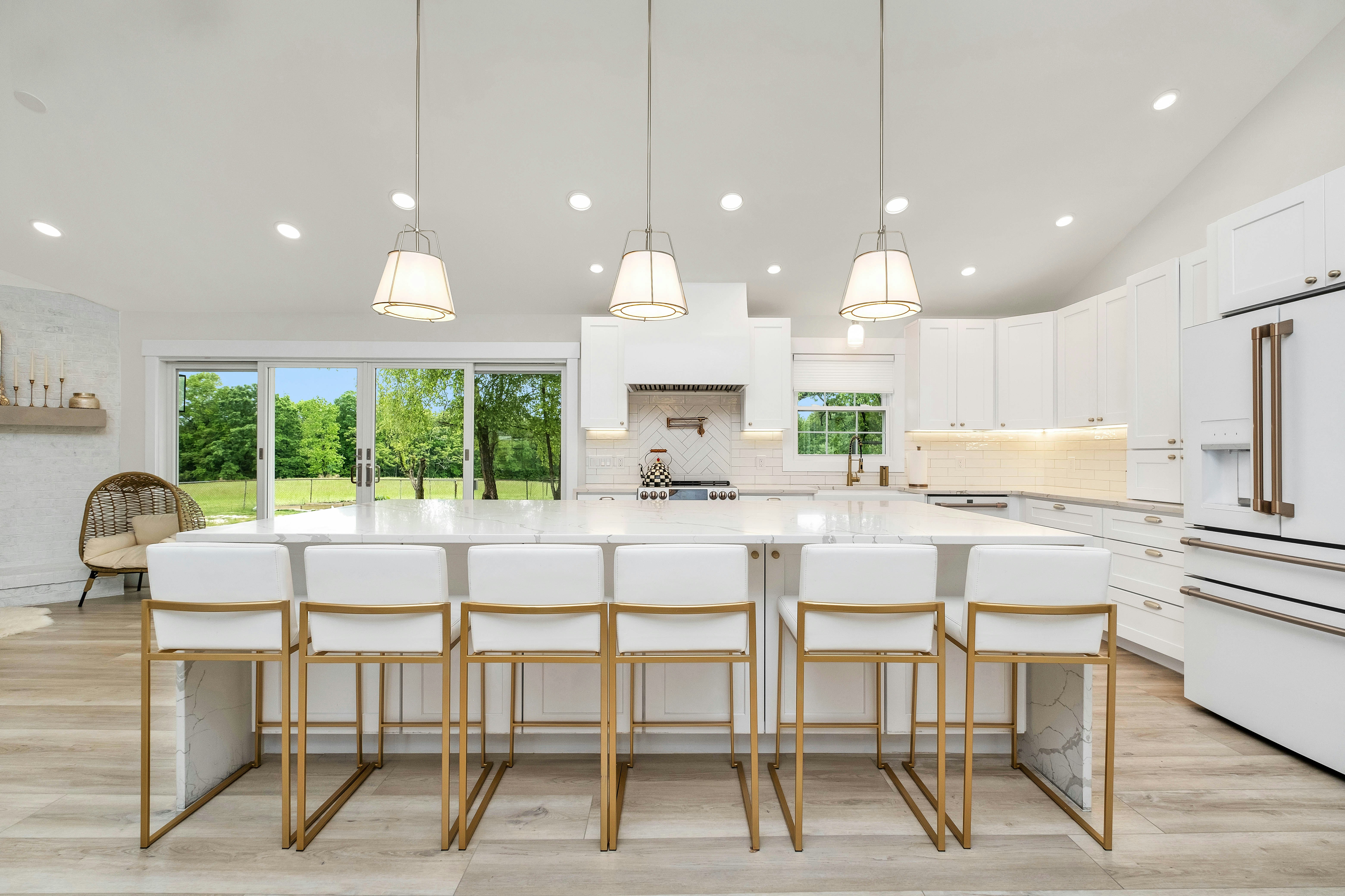 Remodeled open-plan Ballard kitchen with large white quartz island, gold bar stools, and vaulted ceiling