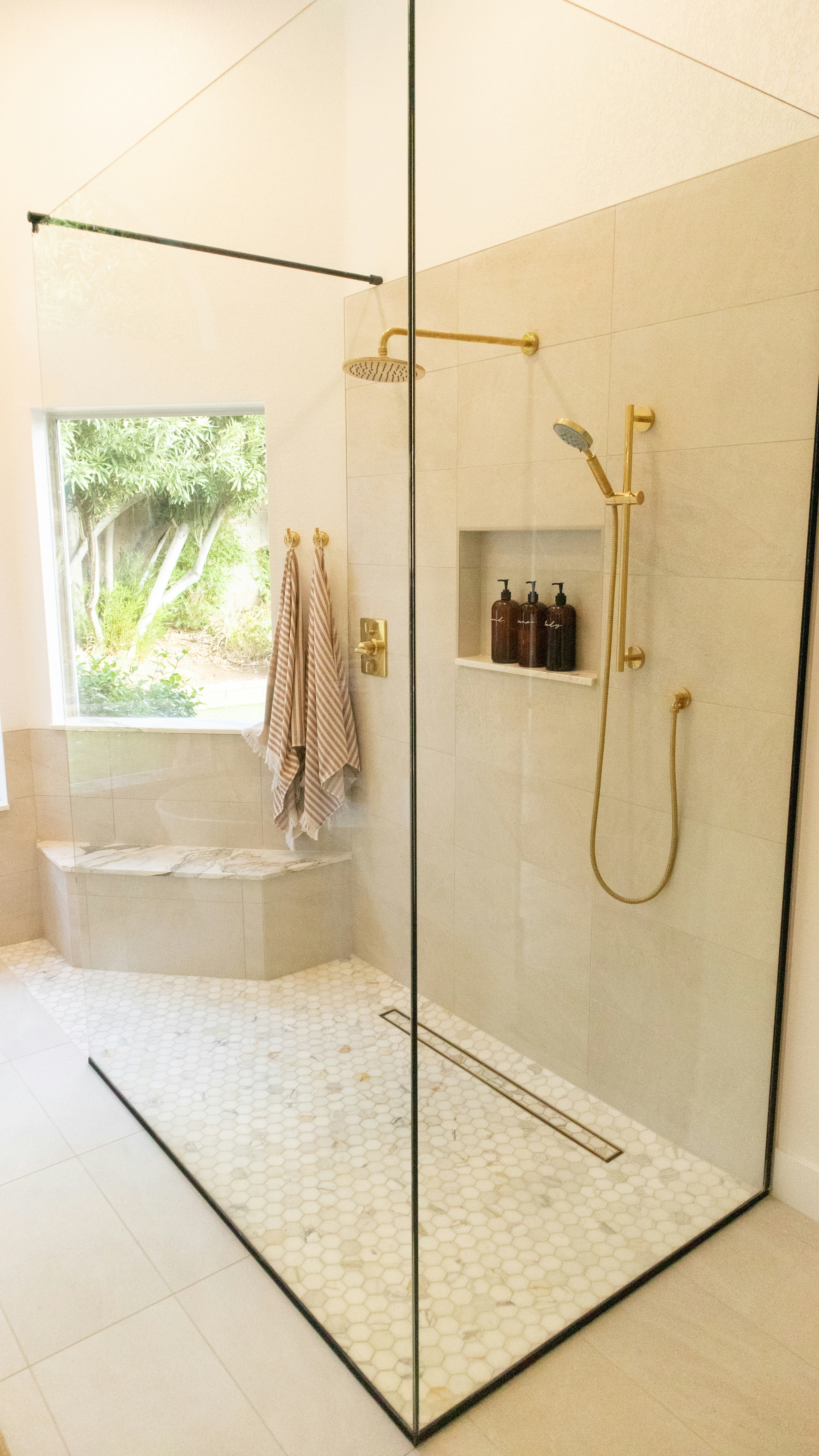 Curbless walk-in shower with large-format porcelain tile and frameless glass enclosure