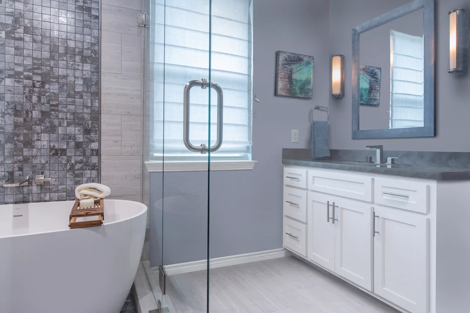 Freestanding soaking tub centered under a window with wall-mount filler faucet and tile surround