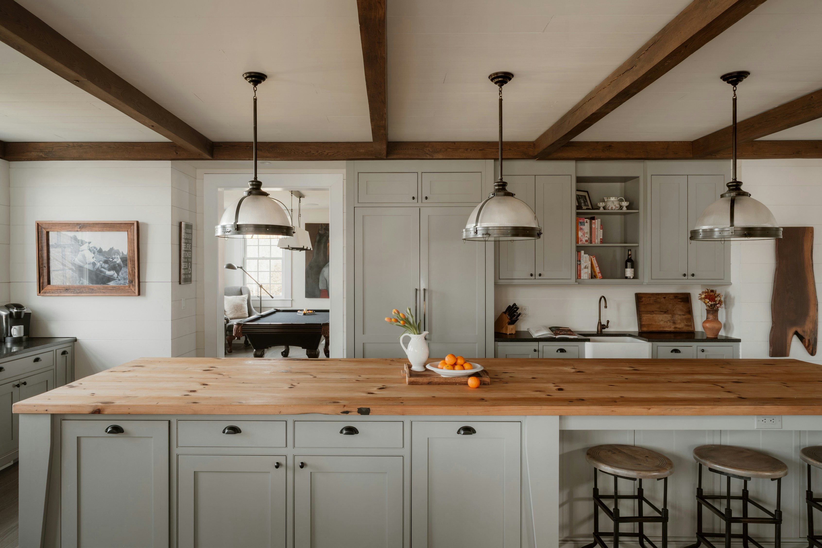 Farmhouse kitchen with sage gray shaker cabinets, butcher block island, and exposed wood ceiling beams