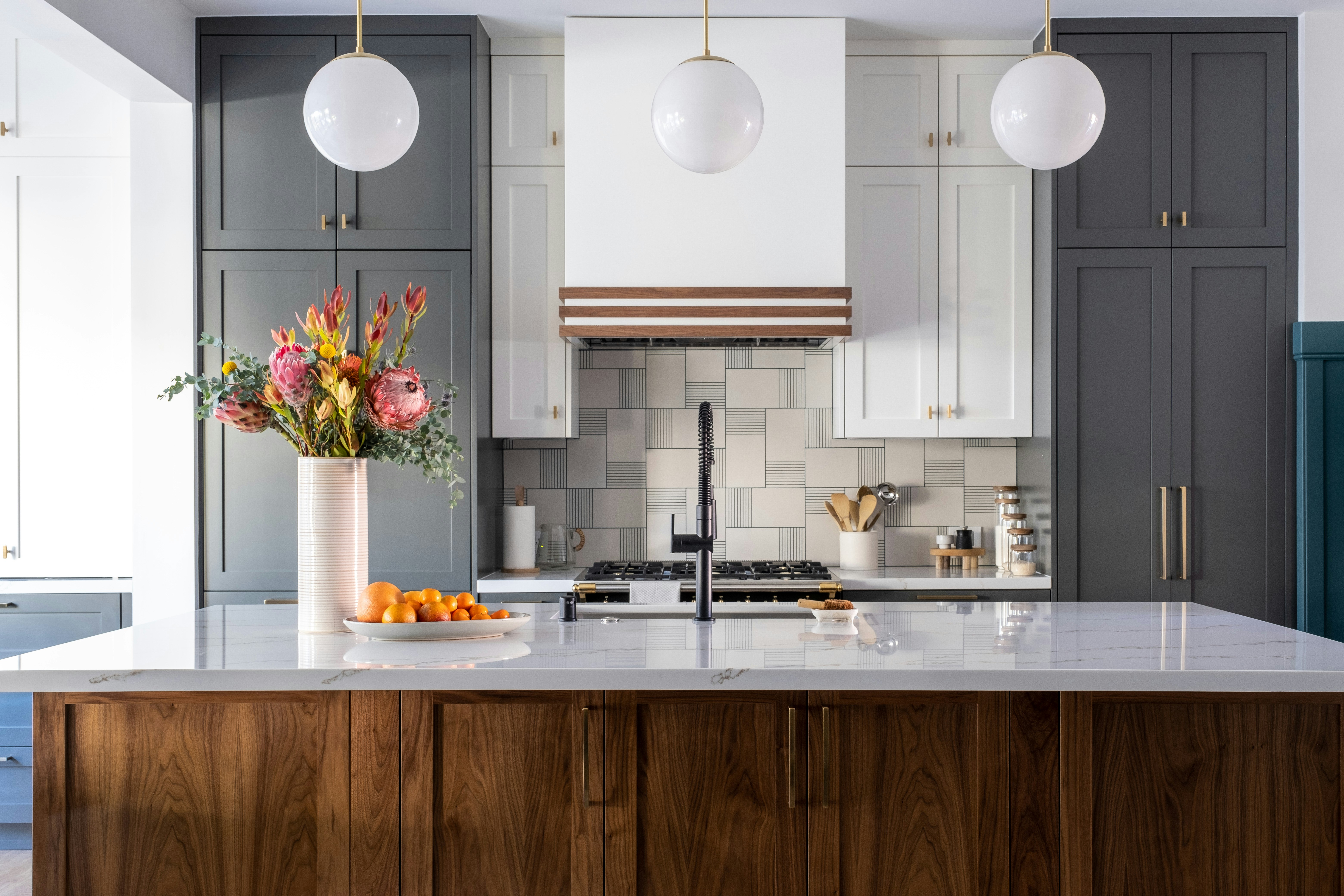 Modern kitchen with charcoal upper cabinets, walnut island base, white quartz countertop, and handmade ceramic tile backsplash
