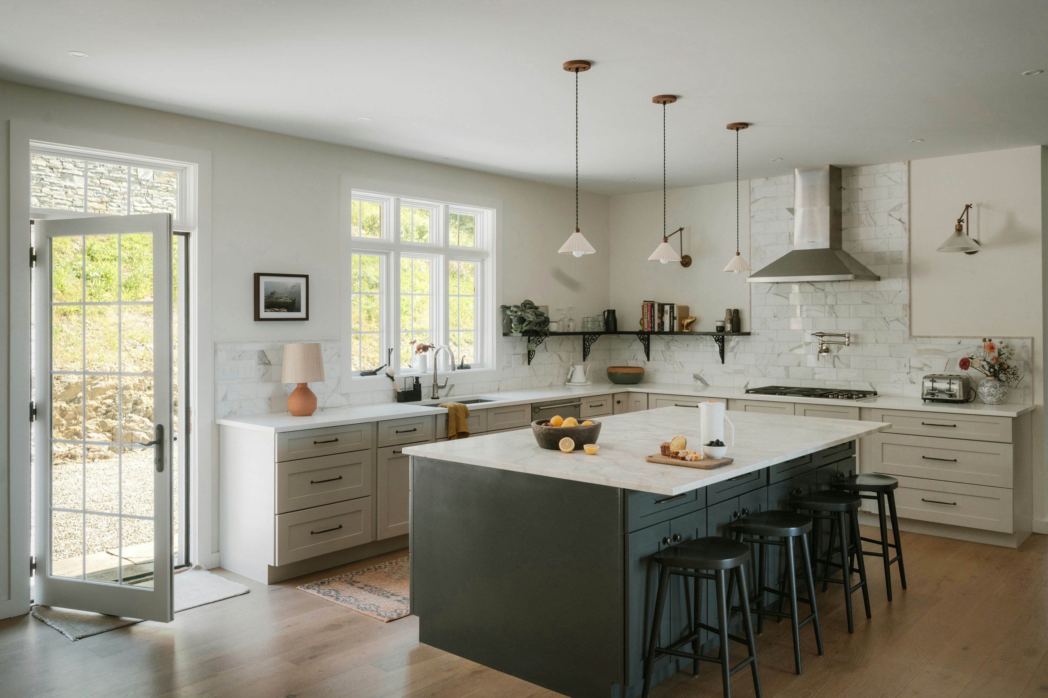Light-filled kitchen with sage green island, white perimeter cabinets, marble tile backsplash, and French doors